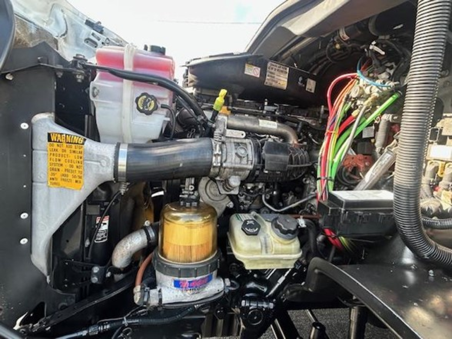  Freightliner Cascadia engine bay showing yellow filter, coolant reservoir, and wiring harnesses.