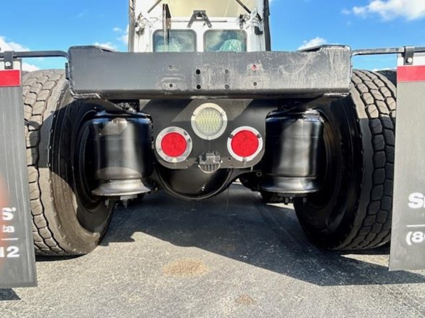 Rear view of a Freightliner Cascadia Evolution truck showing the undercarriage with dual rear axles, air tanks, and red/white lights; no legible labels visible.