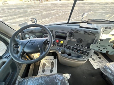 Dashboard and steering wheel view of a Freightliner Cascadia Evolution cab with center console controls and steering wheel badge visible.