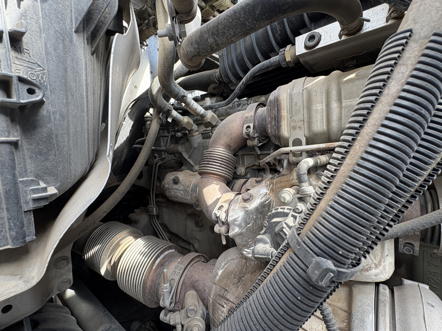 Engine bay view showing turbocharger and intake hoses in a Freightliner Cascadia 126 engine compartment.