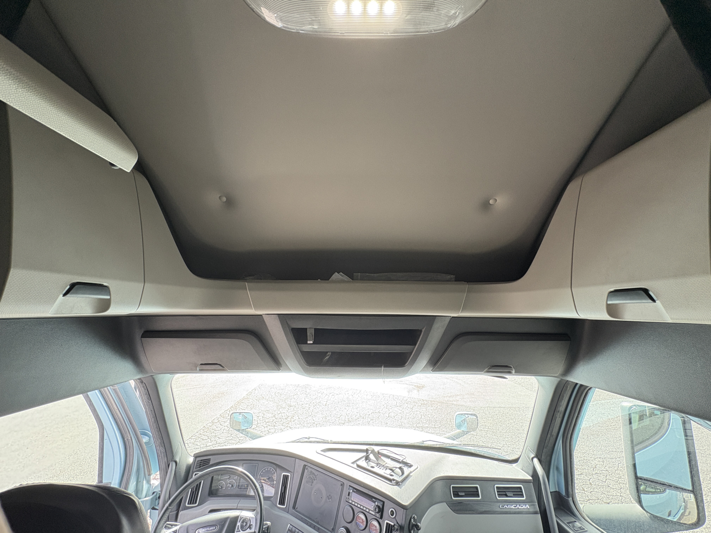 Truck interior ceiling view showing overhead storage compartments and dashboard through windshield