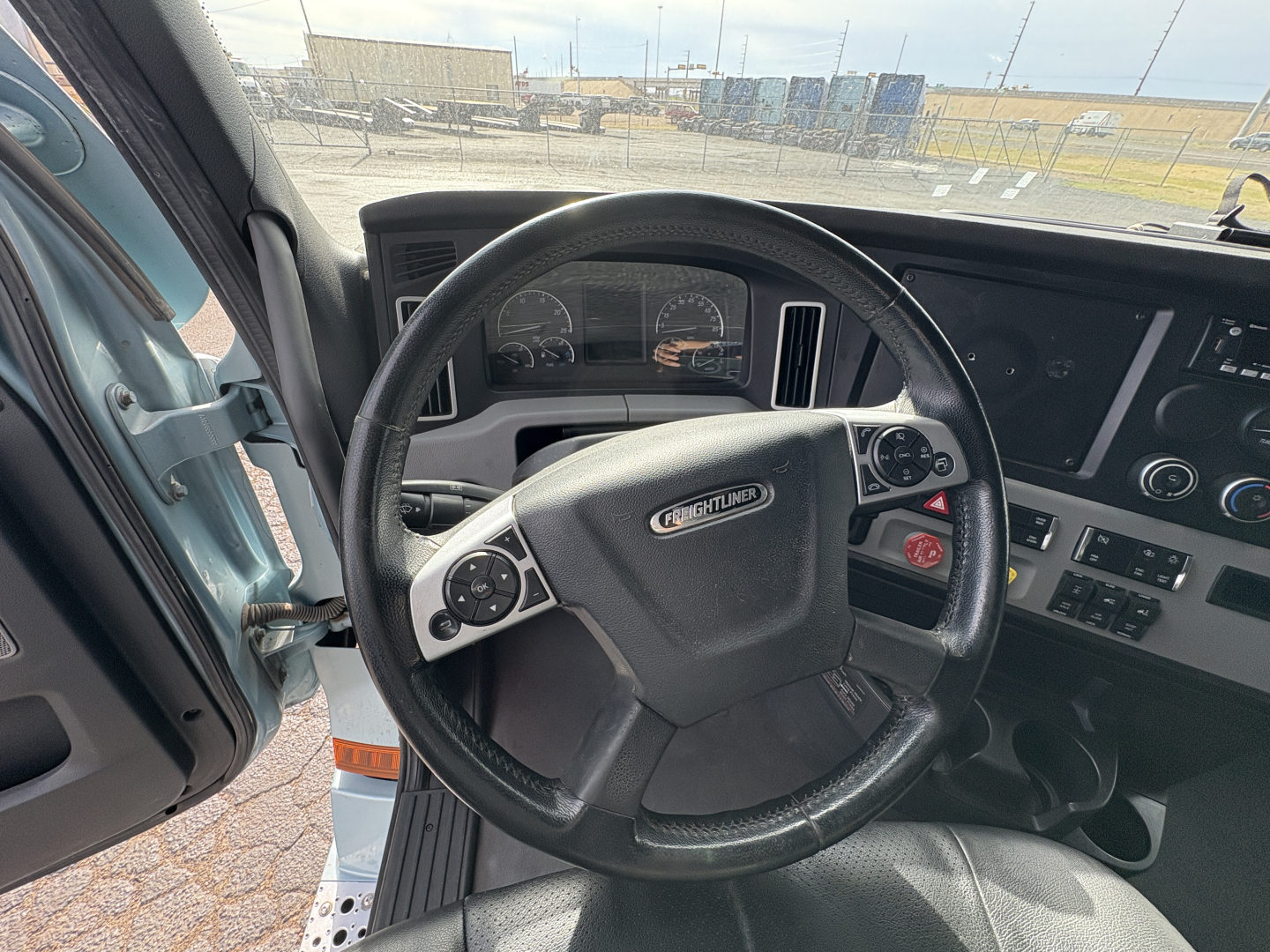 Freightliner steering wheel and dashboard of a Cascadia truck cab. Dashboard gauges visible with steering wheel logo and controls.