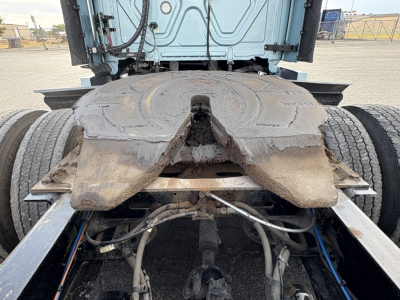 Freightliner Cascadia 126 drivetrain view showing fifth-wheel plate and rear chassis with hoses and cables; mud and wear around the fifth-wheel area.