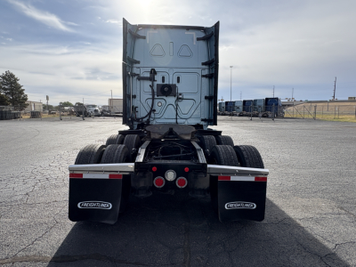 Rear view of a Freightliner Cascadia 126 tractor with dual rear wheels, mud flaps labeled Freightliner, and trailer hitch area visible.