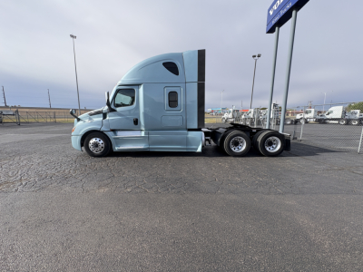 Truck cab side view showing Freightliner Cascadia 126 sleeper with light blue paint and triple rear axles.