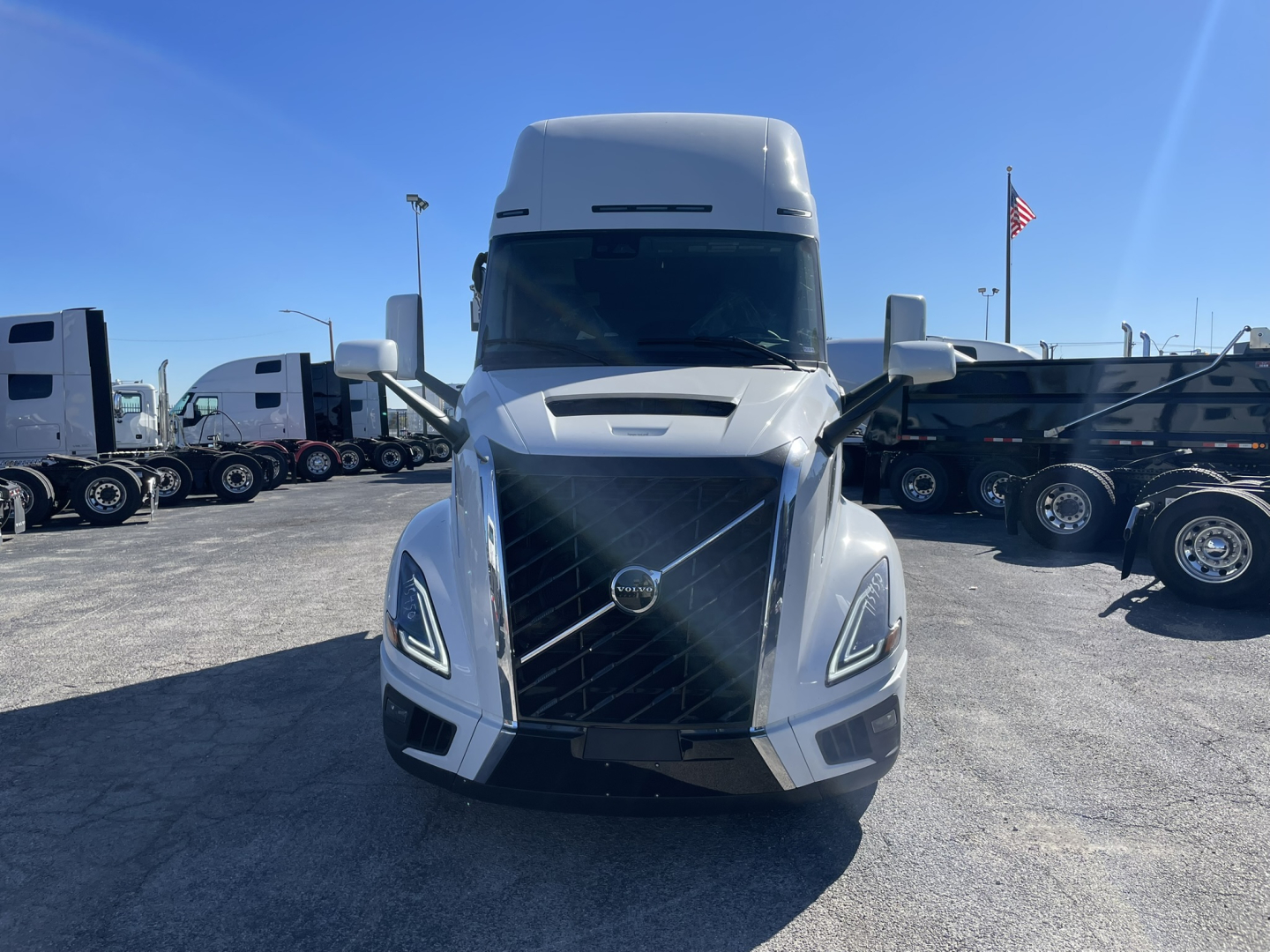 Volvo VNL64T860 truck front view showing bold grille and headlights with US flag in background.