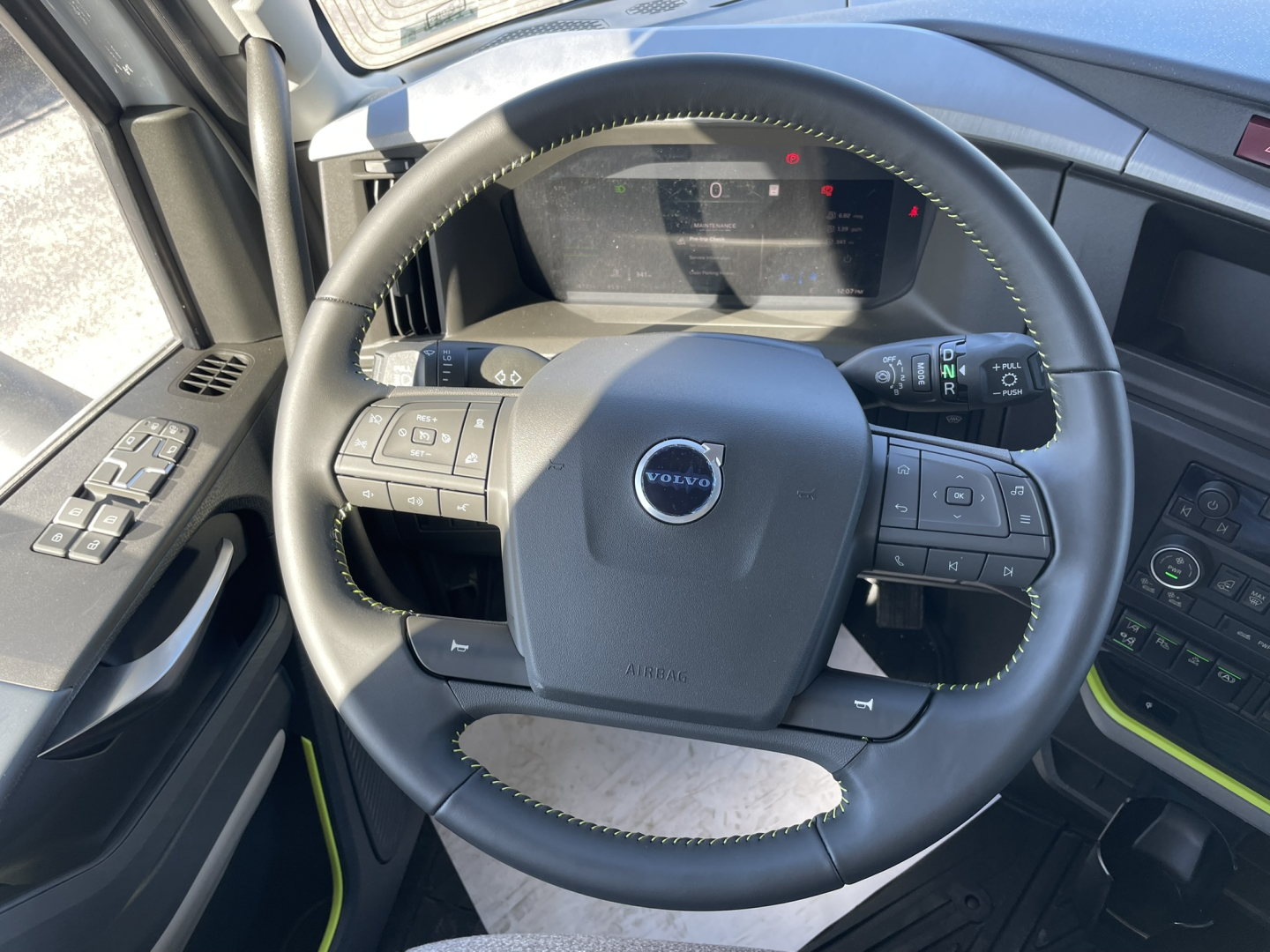 Volvo steering wheel and dashboard view in a new Volvo VNL64T860 truck cab showing steering wheel with controls and digital gauge cluster.