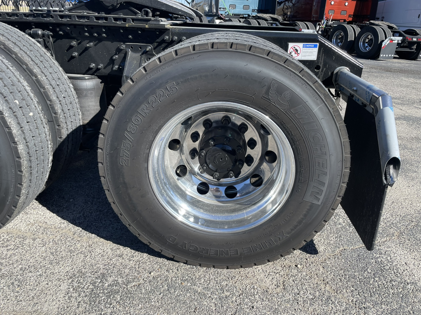 Volvo VNL64T860 truck wheel showing 295/80R22.5 tire and polished steel rim with hub; fender and trailer connections visible.