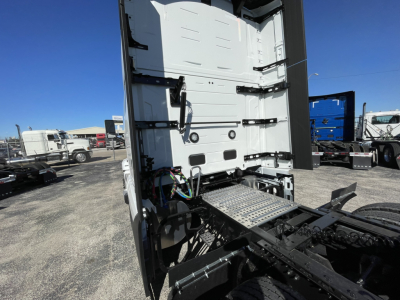 Volvo VNL64T860 cab rear and chassis showing bare area with interior wall, wiring harnesses, and access steps in the truck yard.