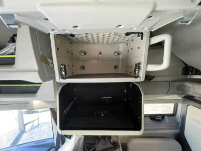 Volvo VNL64T860 cabin storage area showing upper glovebox/open compartment and lower storage bin in a sleeper truck cab.