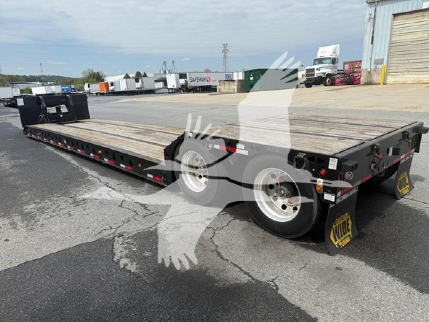 Lowboy trailer with wooden deck showing Talbert mechanical detachable gooseneck components and dual axles with black fenders and yellow KYOTO-style wheel chocks.