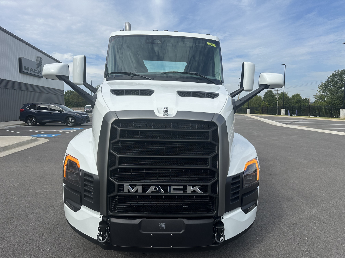 Front view of a white 2026 Mack PR64T truck showing large black grille with MACK lettering, headlights, and mirrors.