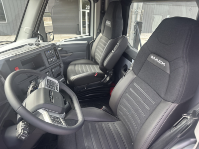 Cab interior of a new 2026 Mack PR64T tractor showing black Mack-branded seats, steering wheel with controls, and dashboard with infotainment screen.