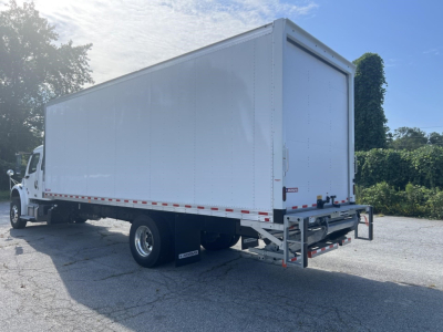Freightliner M2 106 Plus box truck rear-right view showing cargo box and dual rear wheels with rear underrun protection and reflective tape.
