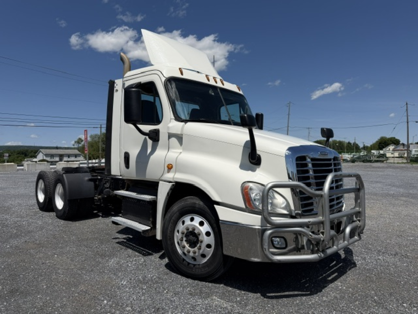 Freightliner Cascadia CA125DC semi truck side/front view showing grille guard, hood, and raised sleeper with white paint.
