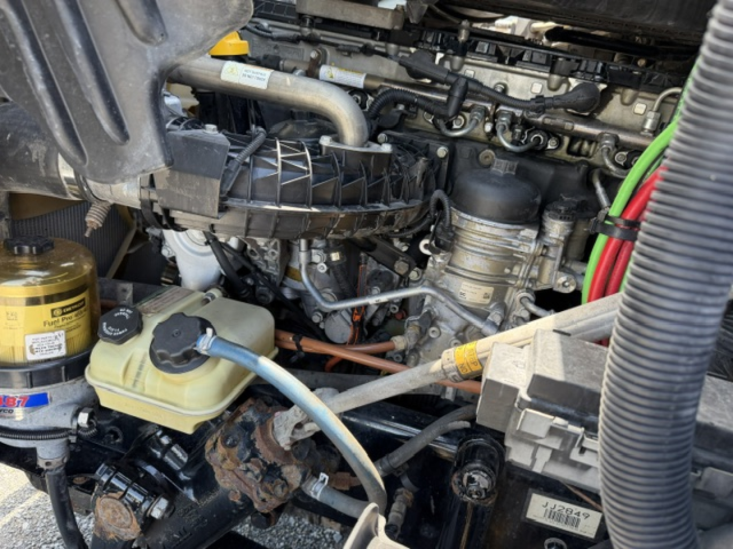 Engine bay of a Freightliner Cascadia 2018 showing coolant reservoir, hydraulic lines, and surrounding components.