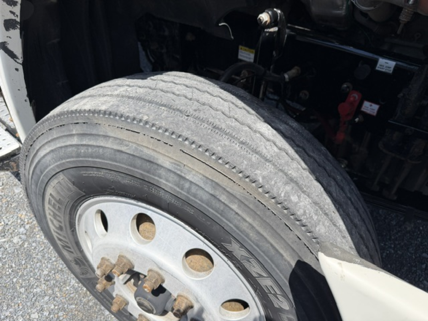 Front wheel and suspension area of a Freightliner Cascadia CA125DC truck showing tire, rim, and wheel hub with some exposed components.