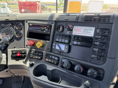 Truck dashboard interior showing multiple gauges, switches, and control panels in a Freightliner Cascadia cab.