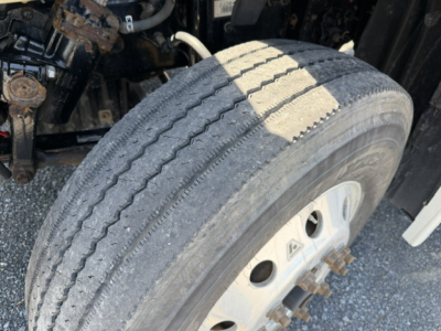 Front wheel and tire of a 2018 Freightliner Cascadia CA125DC showing tread wear and wheel rim, partial suspension components visible.