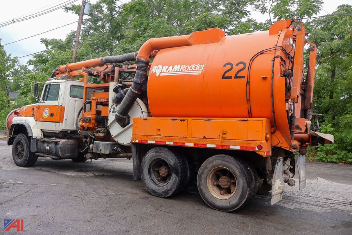 Orange Ford LTS8000 sewer truck with large cylindrical tank and piping, number 22 on the side, RAMRocker logo on tank, white cab with orange stripe.