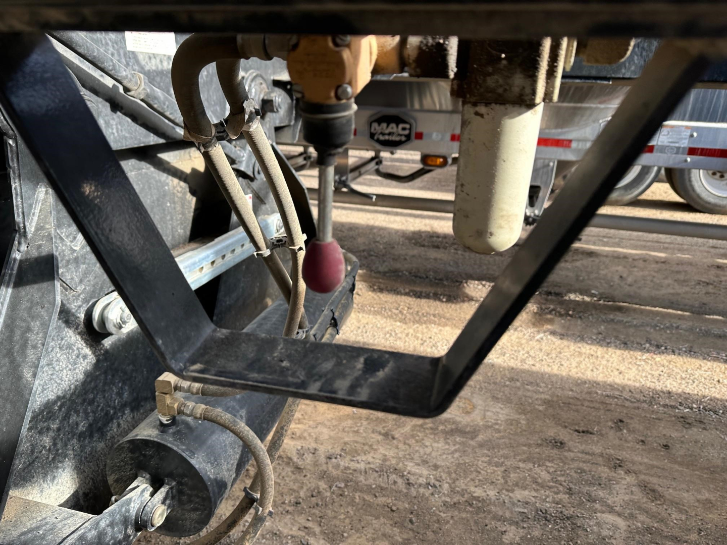 Trailer hitch area showing hydraulic lines and hydraulic ram components for bottom dump with electric tarp system; label MAC and wiring visible.