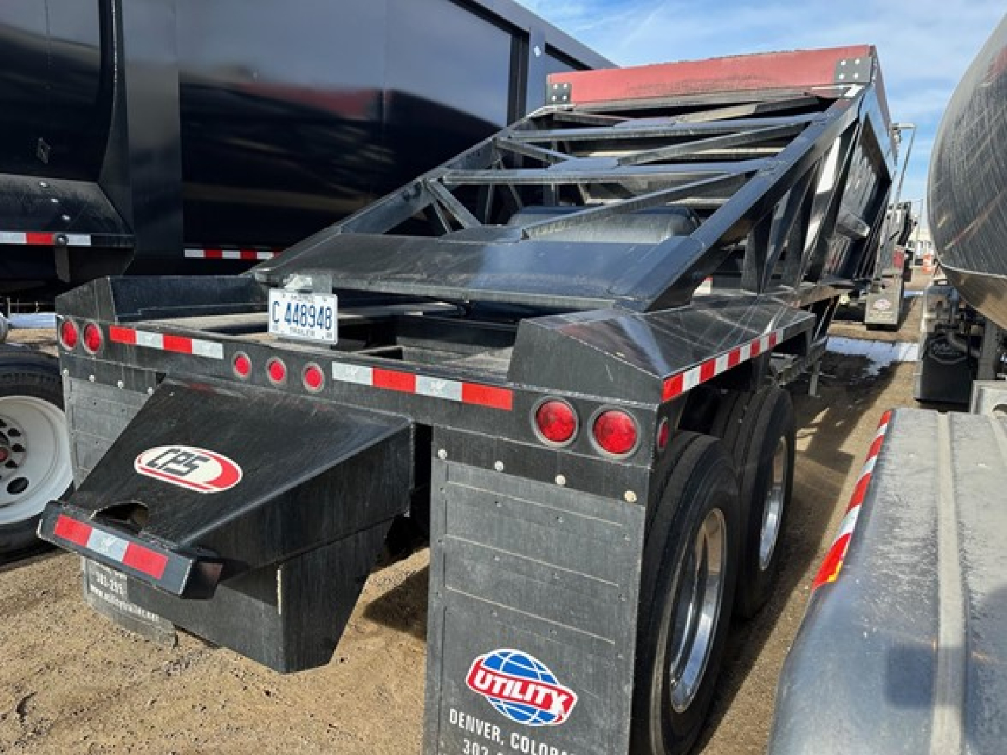 Bottom dump trailer with air ride support showing rear view with tandems and toolbox, Utility logo plate, license plate C 448946.