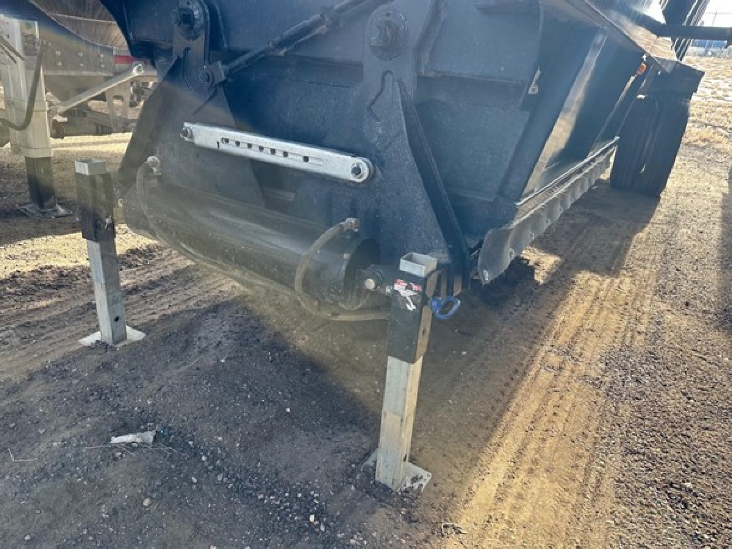 Bottom dump trailer undercarriage with landing legs and hydraulic components visible.