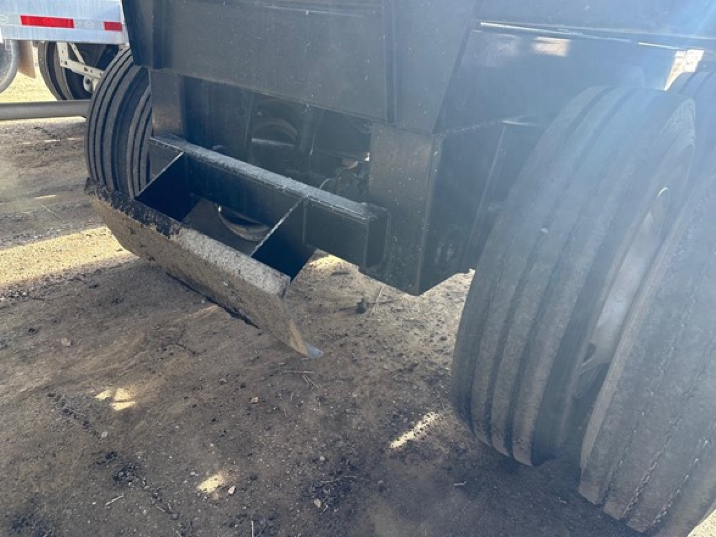 Dump trailer underside showing air ride bottom dump mechanism and dual rear axles with heavy-duty tires.