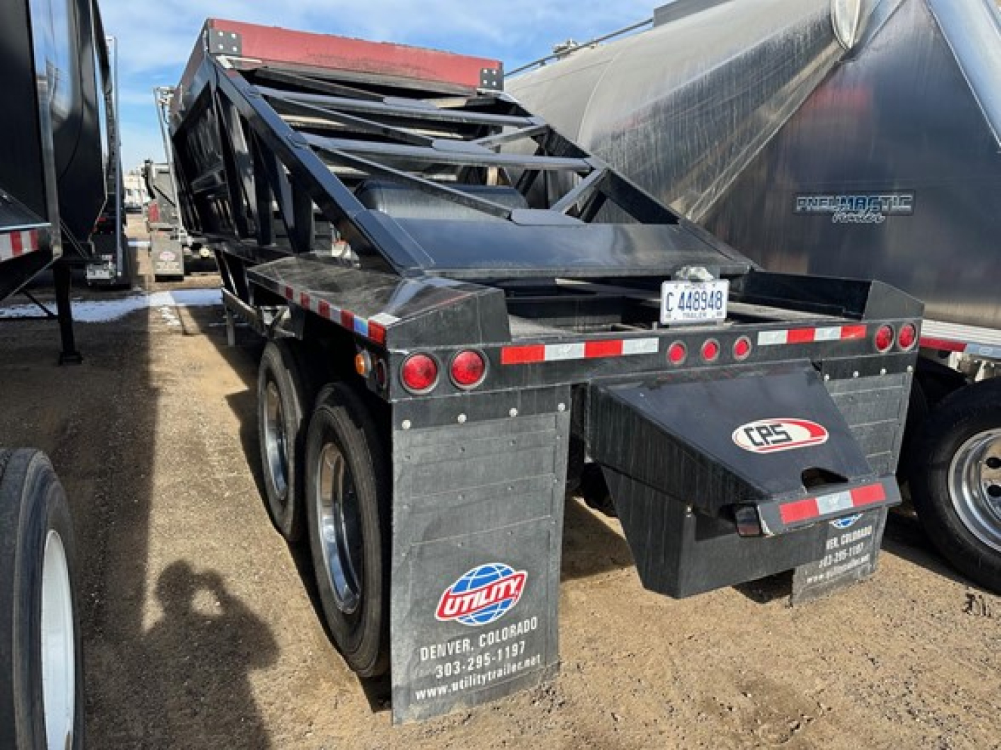 CPS air ride bottom dump trailer showing rear view with bumper and taillights, stacked frame components, black metal finish, Utility logo on mudflap, Denver, CO contact sticker.