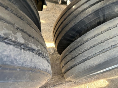 Two rear tires of a dump trailer with visible tread and dirt, viewed from above.