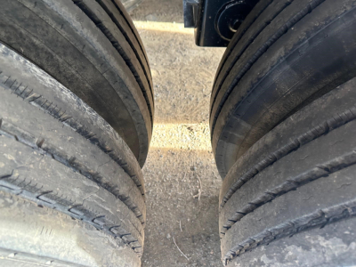 Trailer air-ride bottom dump with dual tandem axle wheels and heavy-duty tires; view focused on the gap between left and right wheel sets.