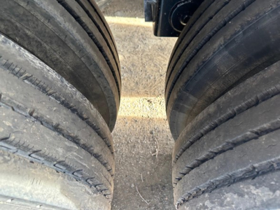 Rear view of dual truck tires with tread grooves visible in a bottom-dump trailer.