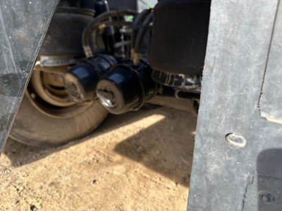 Bottom dump trailer wheel area showing hydraulic hoses and suspension components.