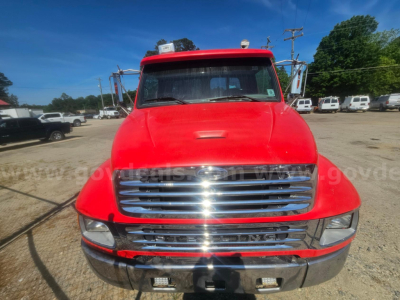 Front view of a red 2006 Sterling Acterra truck in a dealership lot. Chrome grille, bumper, headlights, and windshield with some reflection. Text on the image not clearly legible.