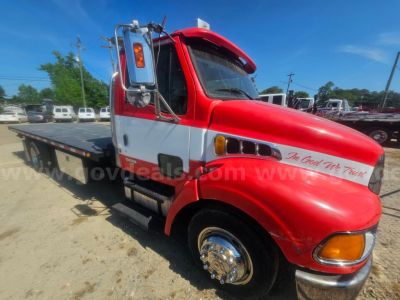 Truck cab side view showing red Sterling Acterra tow truck with flatbed and chrome wheels.