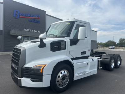 Mack PR64T truck front/side view in a dealership lot with white cab and black grille Fitted with dual rear axles and front fender mirrors.