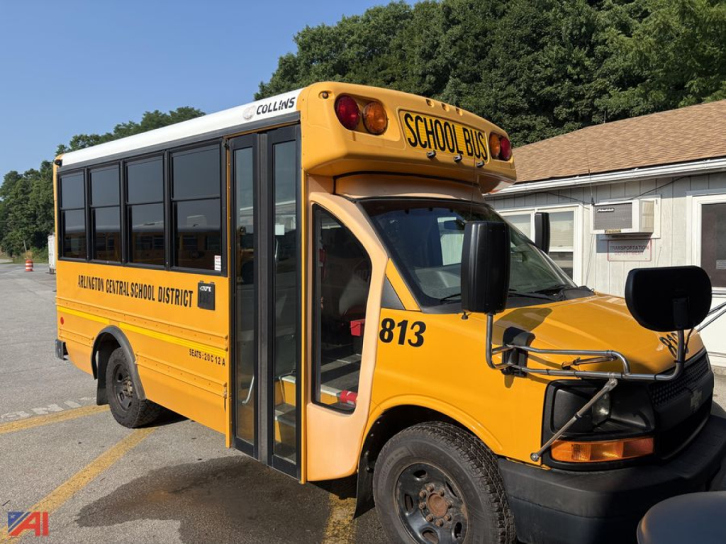 Yellow Chevrolet Express G3500 school bus side view, front cab with extended hood, school bus signage and black passenger doors, wheel wells, and district lettering on side.