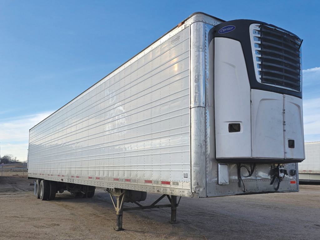 Reefer trailer with a Carrier refrigeration unit at the front, aluminum body panels, two axles, landing gear in foreground.