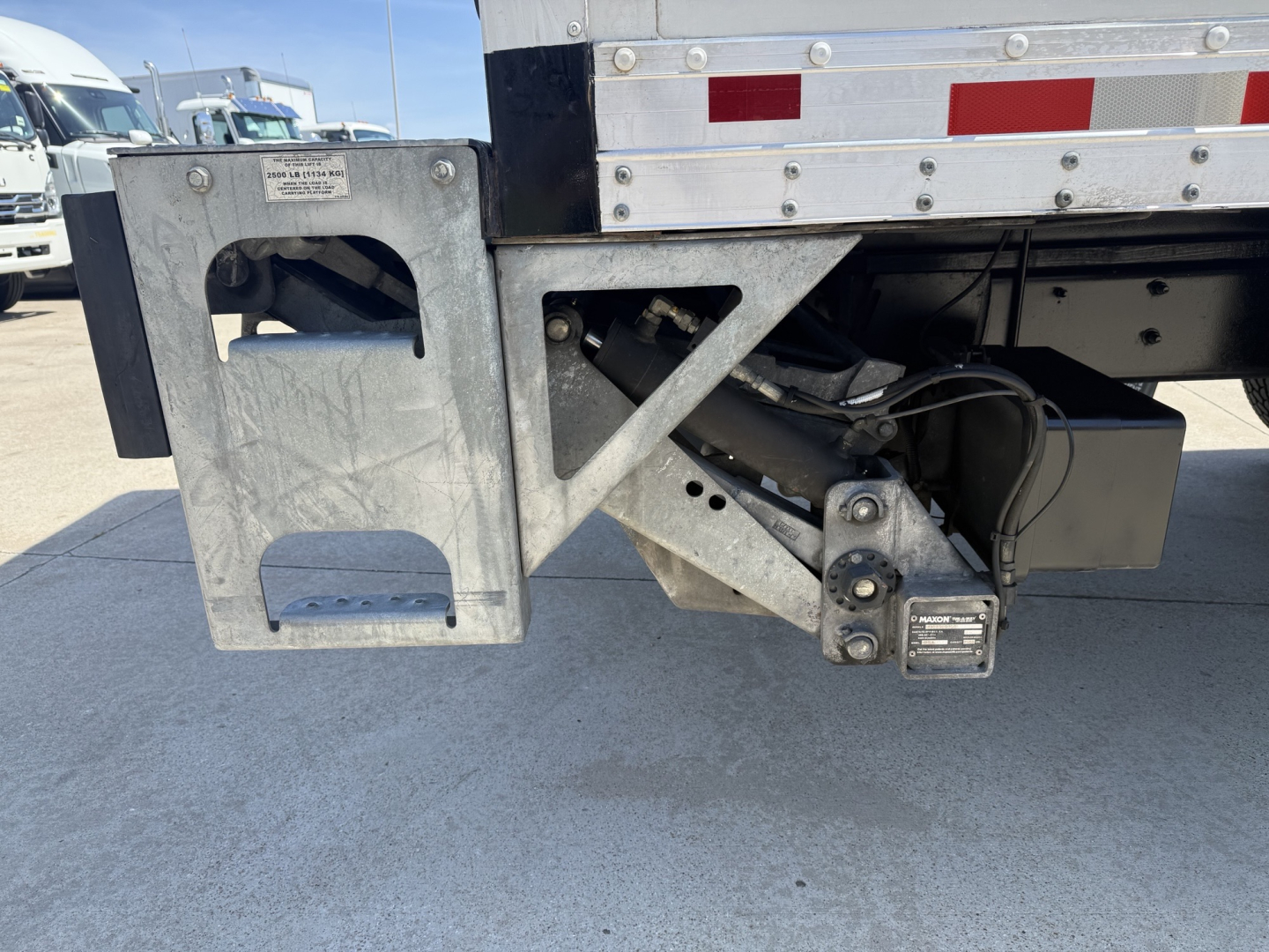 Rear undercarriage of a Freightliner M2 trailer unit showing metal toolbox, hitch, and hydraulic lines.