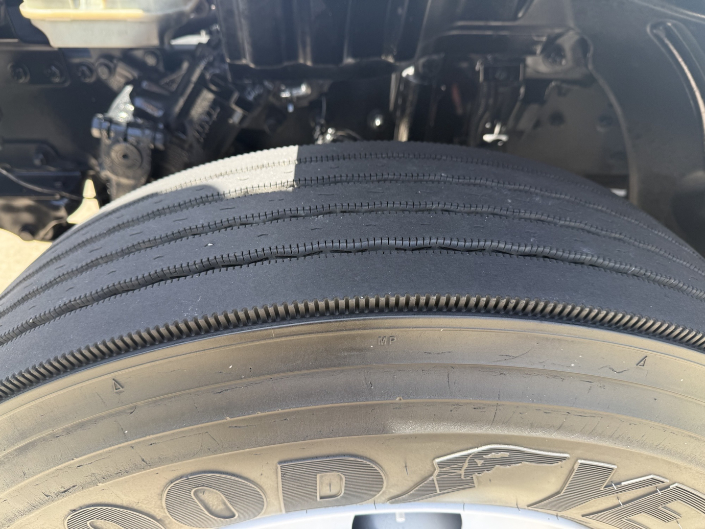 Wheel and front suspension area of a 2020 Freightliner M2 showing Goodyear tire with visible tread and partial engine bay components.