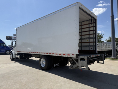 Freightliner M2 box truck rear quarter view showing cargo box and rear doors, side view mirrors, and wheel on concrete lot.