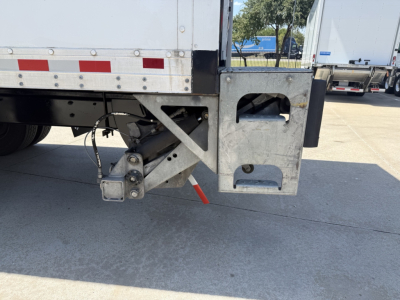 Freightliner M2 rear underbody area with metal brackets and a hitch assembly. Visible components include a trailer hitch assembly, mounting brackets, and a red strap or tag hanging.