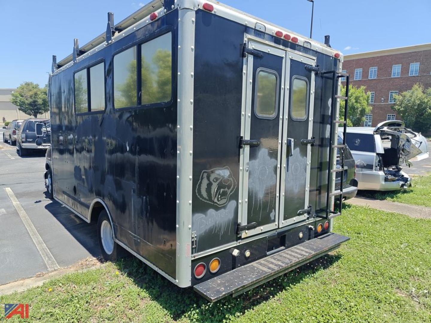 Box truck rear view showing dual rear doors, metal ramp/step, and reflective trim on black cargo body.