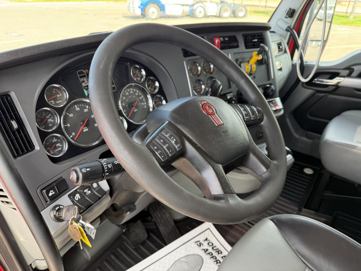 Kenworth T880 cockpit showing steering wheel with Kenworth emblem and instrument cluster visible.