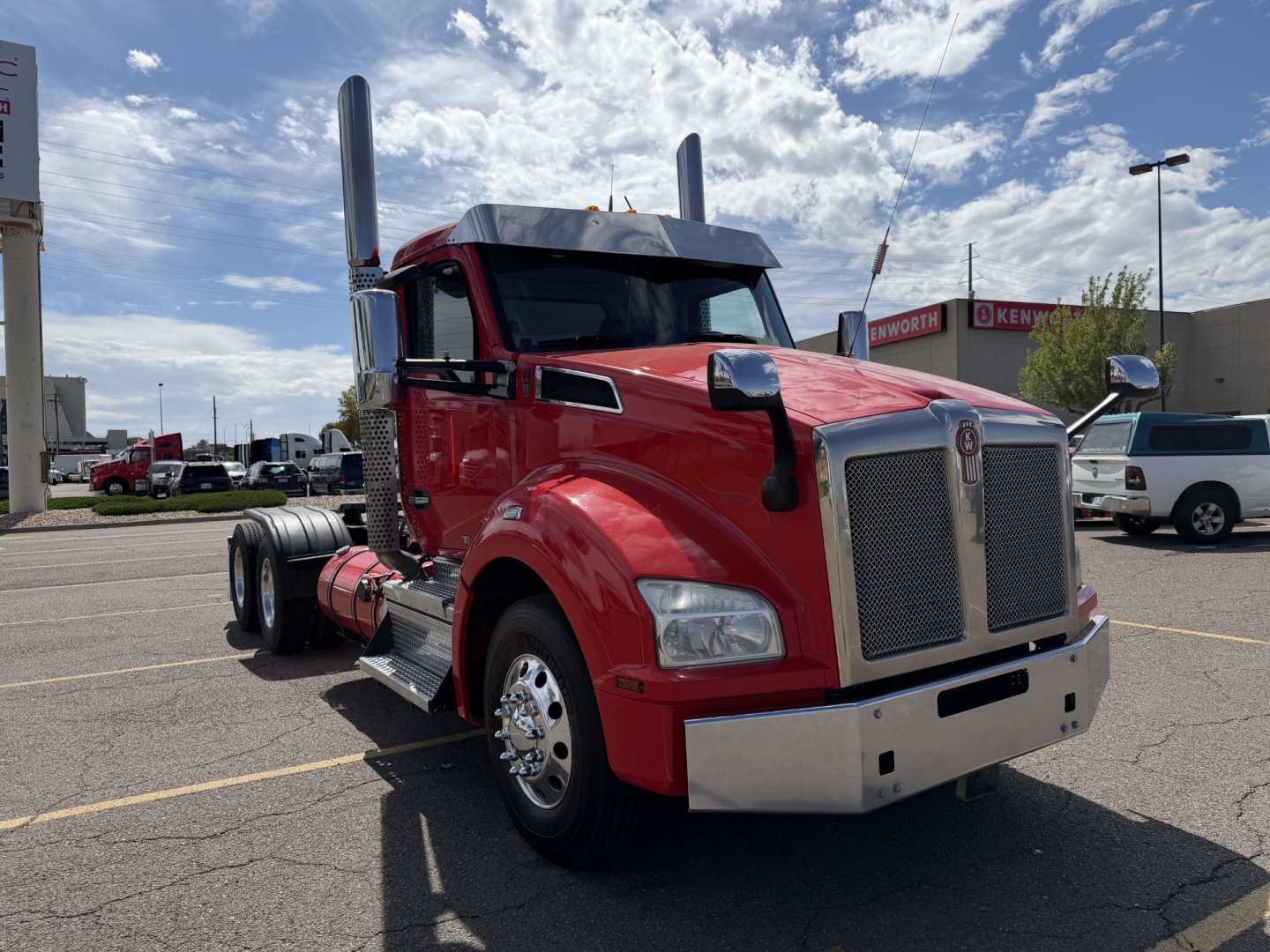 Kenworth T880 conventional daycab truck in red with chrome grille, dual tall exhaust stacks, large front bumper, and polished wheels.