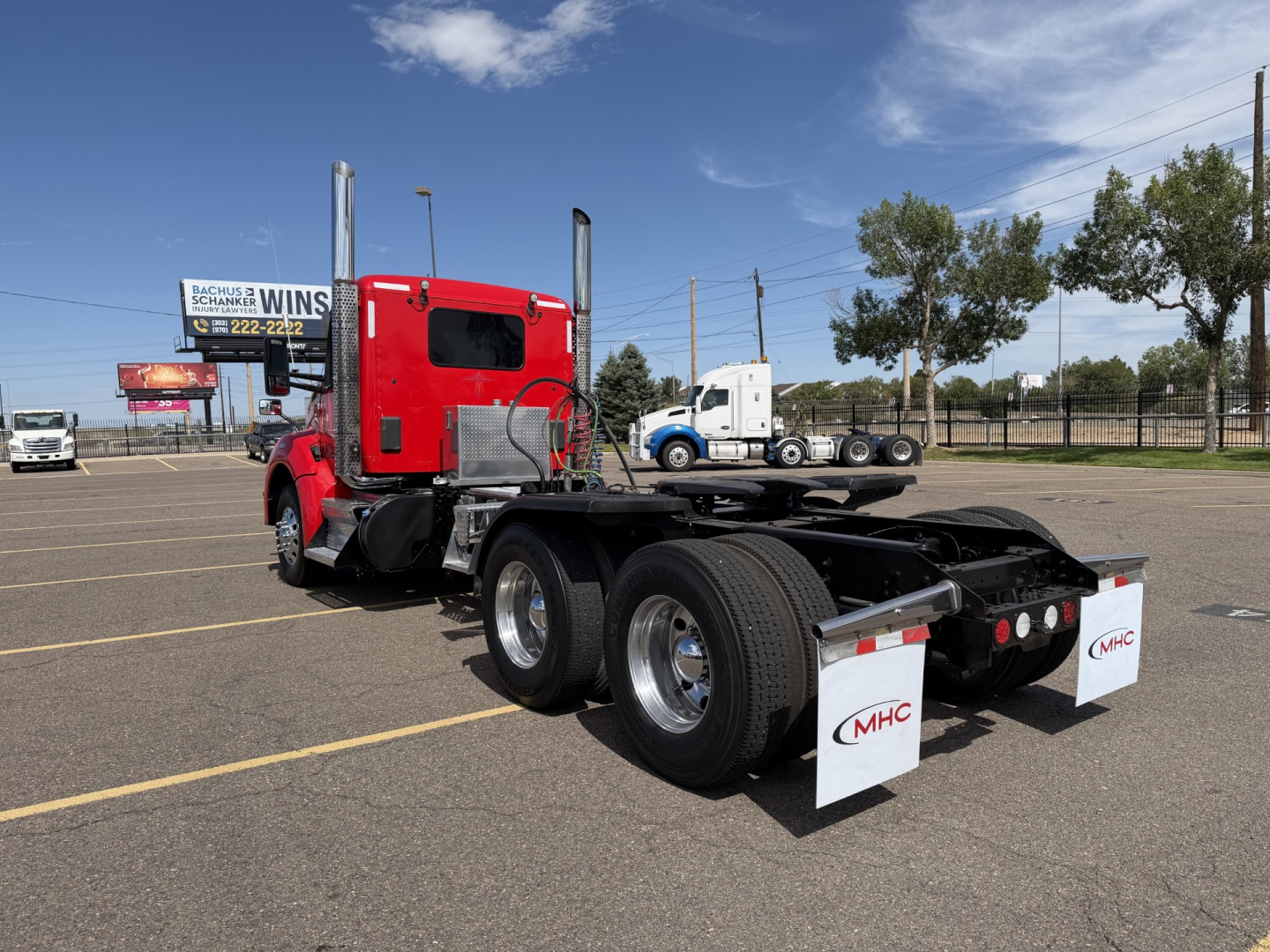 Kenworth T880 vertical exhaust conventional daycab truck chassis rear view showing dual rear axles and mud flaps.