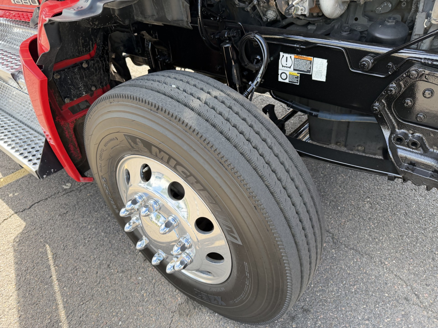 Front left wheel of a 2020 Kenworth T880 conventional daycab showing Michelin tire and wheel assembly with axle components and part of the chassis.