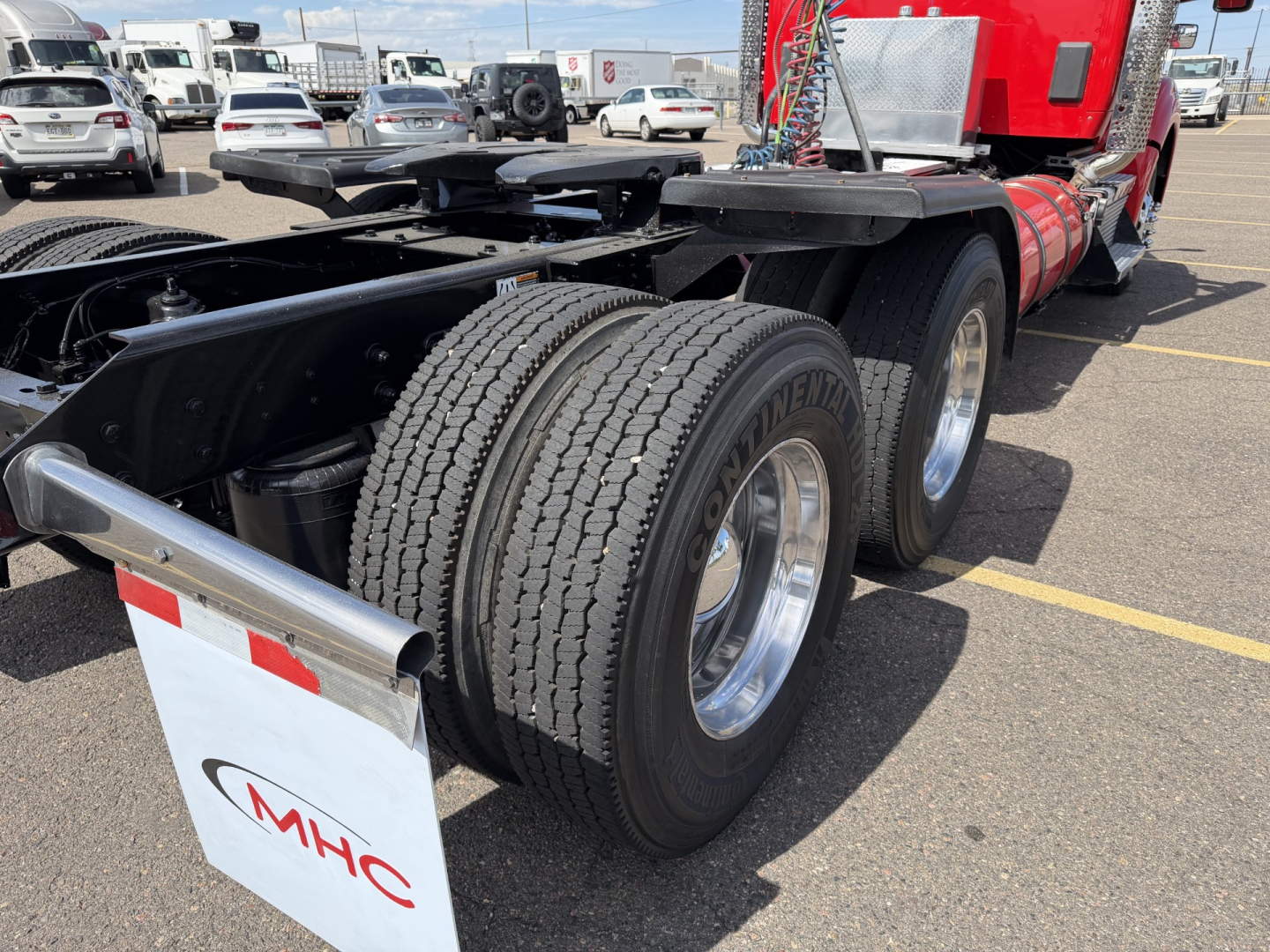 Kenworth T880 truck rear dual axle wheels and fifth wheel area with red cab and chrome fenders; visible tires and dual rear wheels.