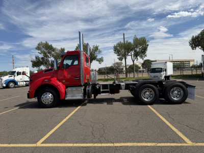 Kenworth T880 daycab truck side view showing chassis and dual rear axles, red cab with chrome exhaust stacks, daytime parking lot