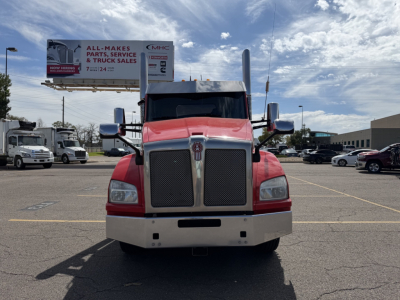 Front view of a red 2020 Kenworth T880 truck with chrome grille, bumper, and large side mirrors in a parking lot.